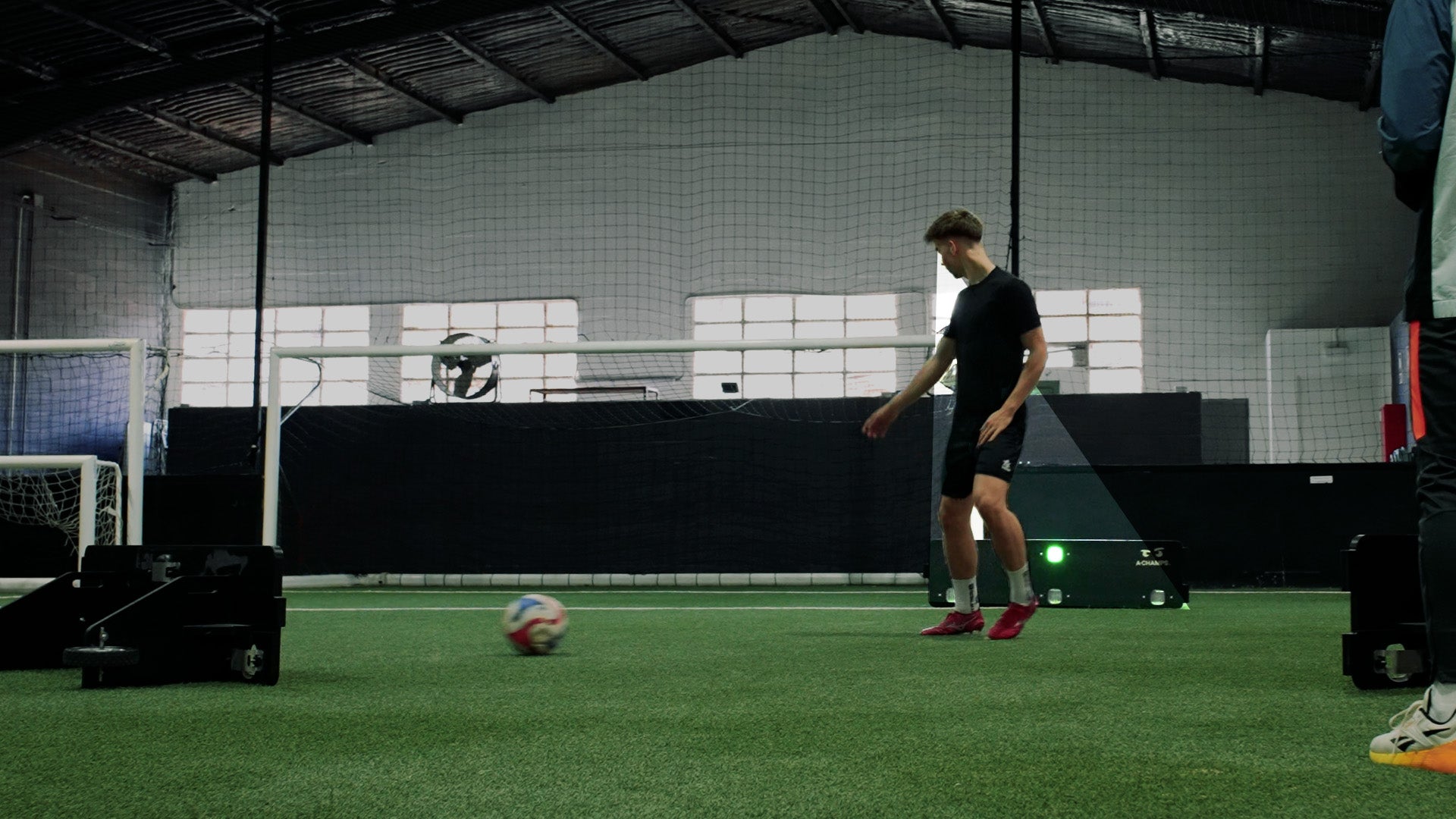 Male player using Goal Station rebounder in indoor facility.